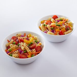 Two bowls of pasta salad, with fusilli, cherry tomatoes, carrots and other fresh vegetables