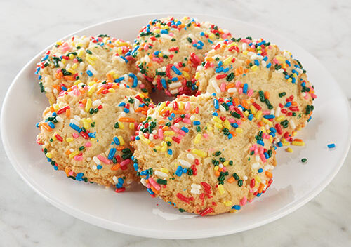 Five chewy cookies with colorful sprinkles on a plate