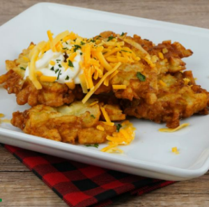 Potato latkes with cheese and sour cream on a square plate
